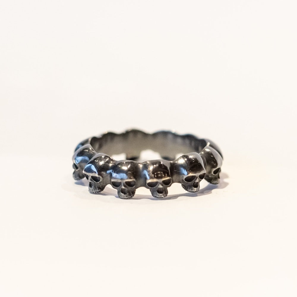 An eternity band of carved skulls made in blackened sterling silver.
