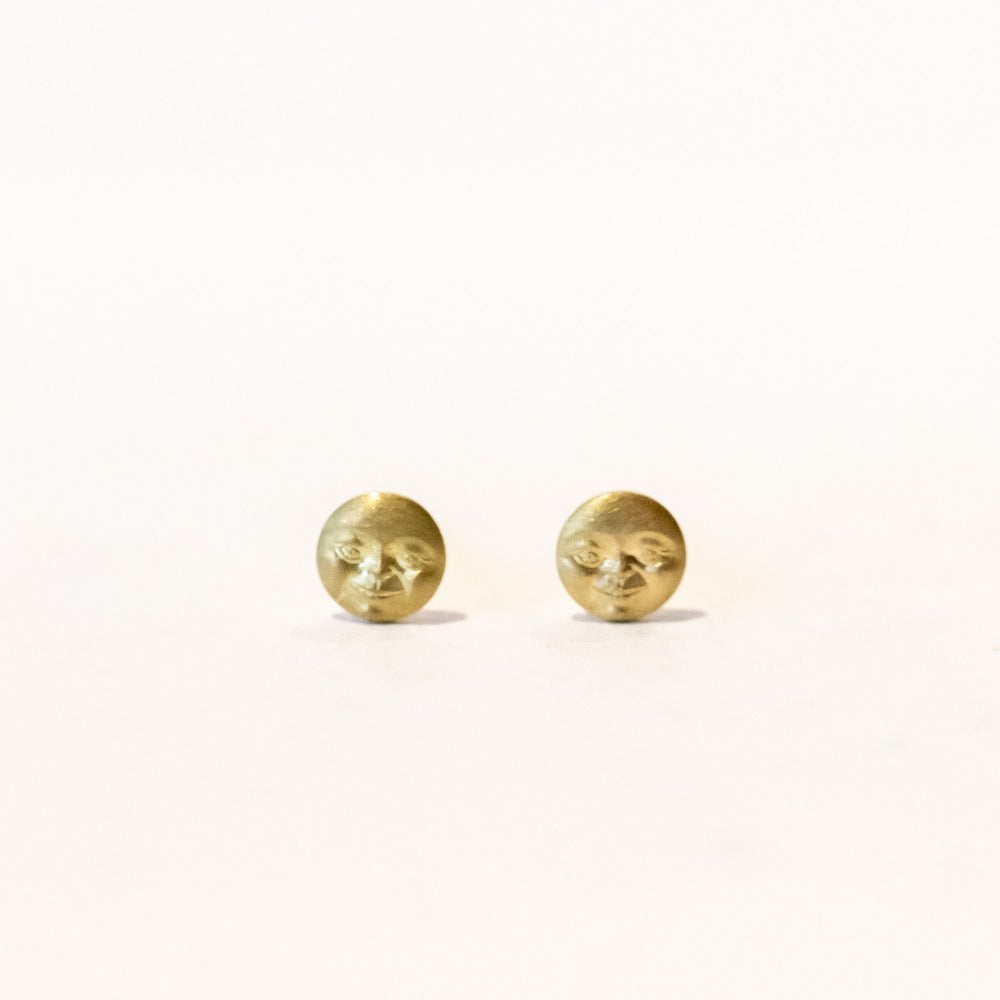Tiny full moon gold stud earrings with faces, front view.