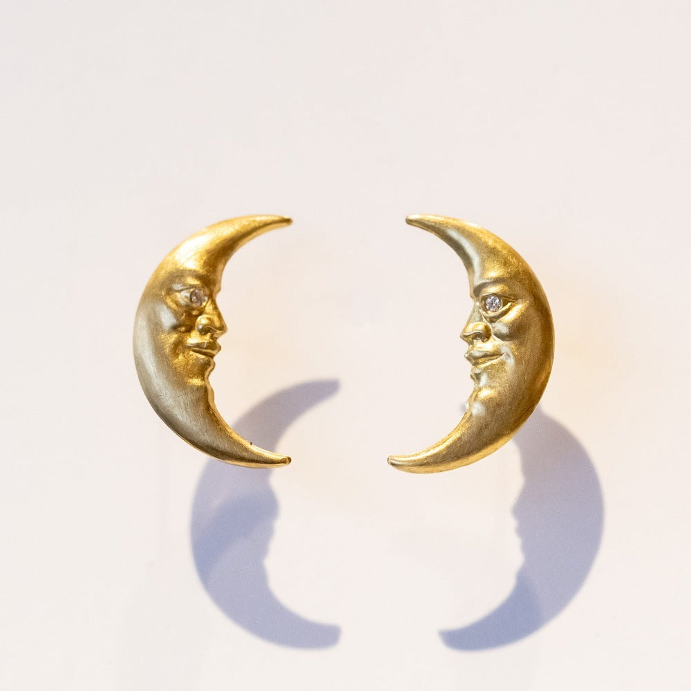 Carved crescent moon stud earrings made in yellow gold, with faces and diamond eyes.