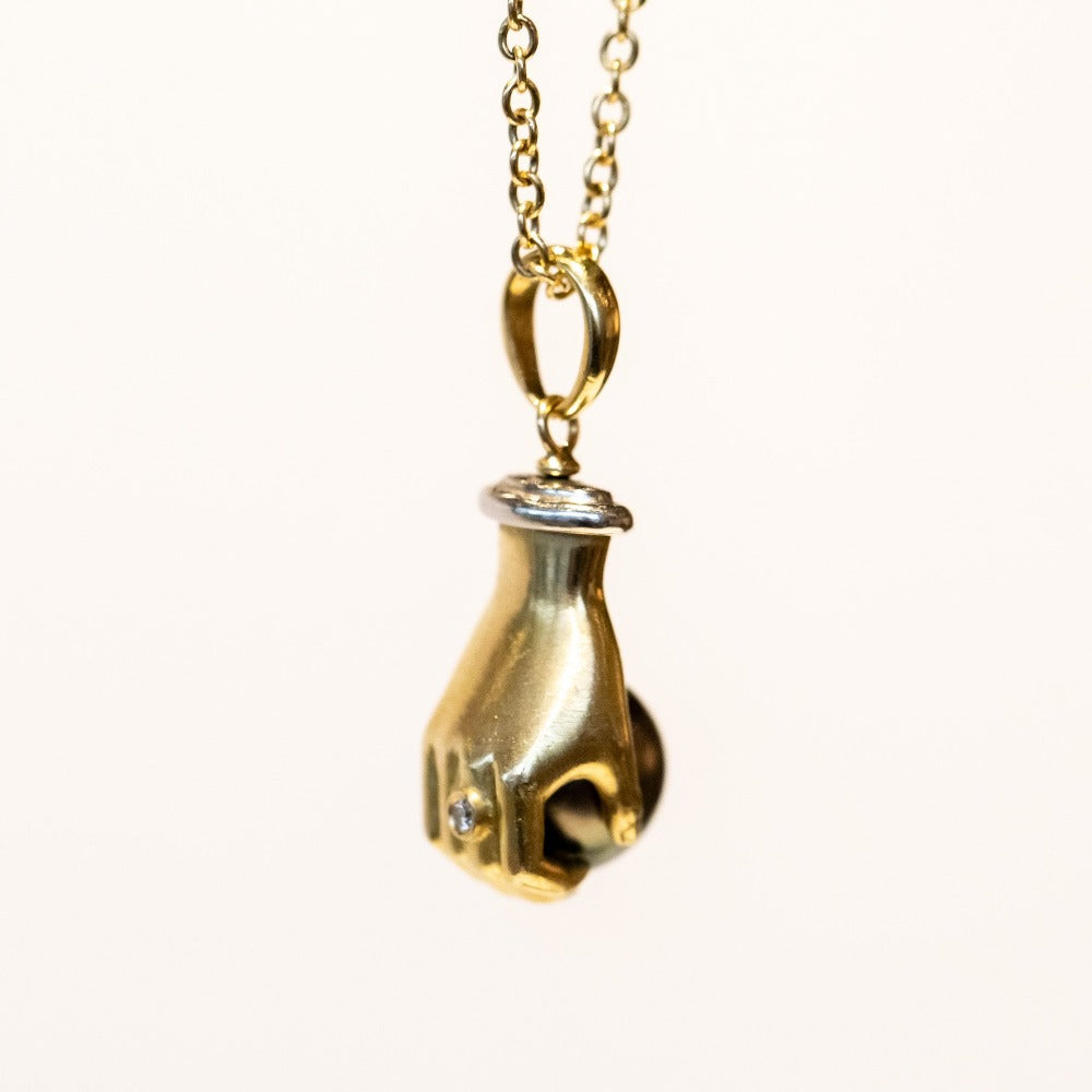 A yellow gold carved hand pendant holding a black Tahitian pearl.