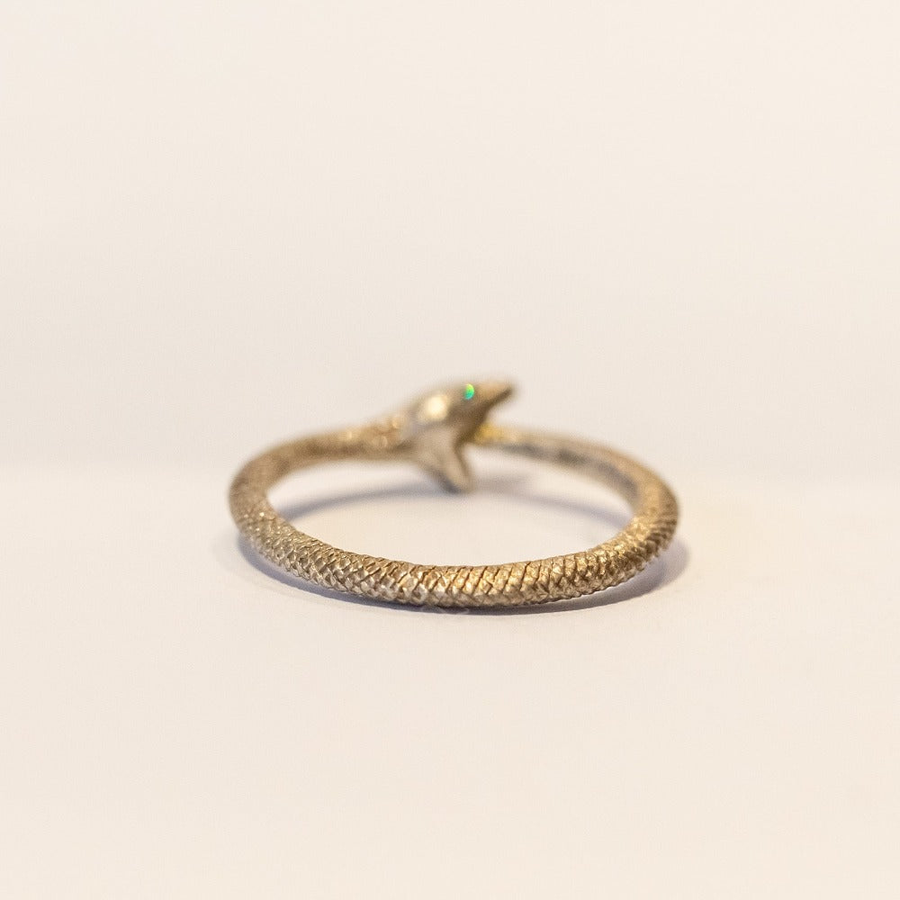 An intricately carved sterling silver ouroboros snake ring with diamond eyes.