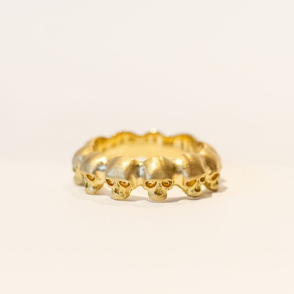 A yellow gold eternity band made up of tiny sculpted skulls.