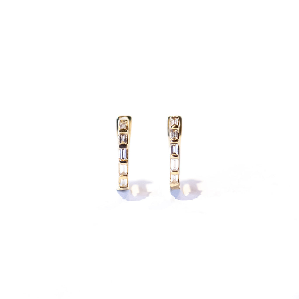 Petite gold hoop earrings set with baguette cut diamonds, front view.