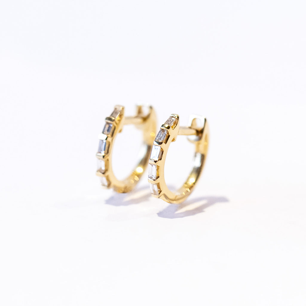 Petite gold hoop earrings set with baguette cut diamonds, front view.