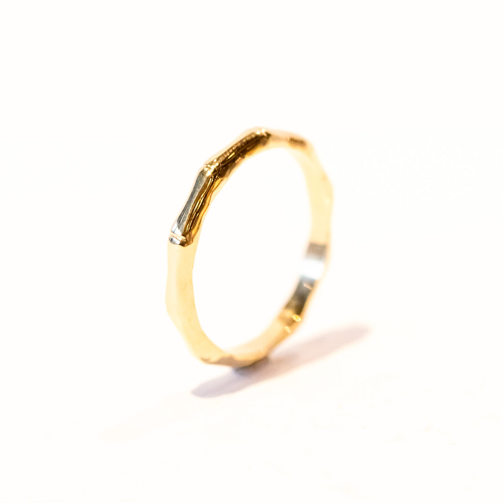 A yellow gold band carved into bamboo design encircling the finger.