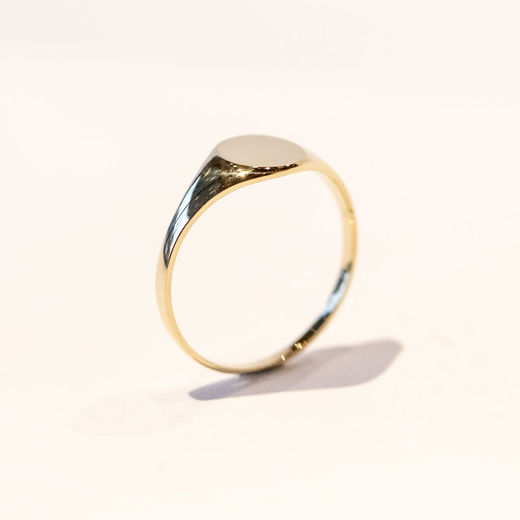 A dainty gold signet ring with a classic oval face.