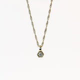 a dainty hexagon shaped pendant set with a round diamond hangs on a delicate gold chain necklace.