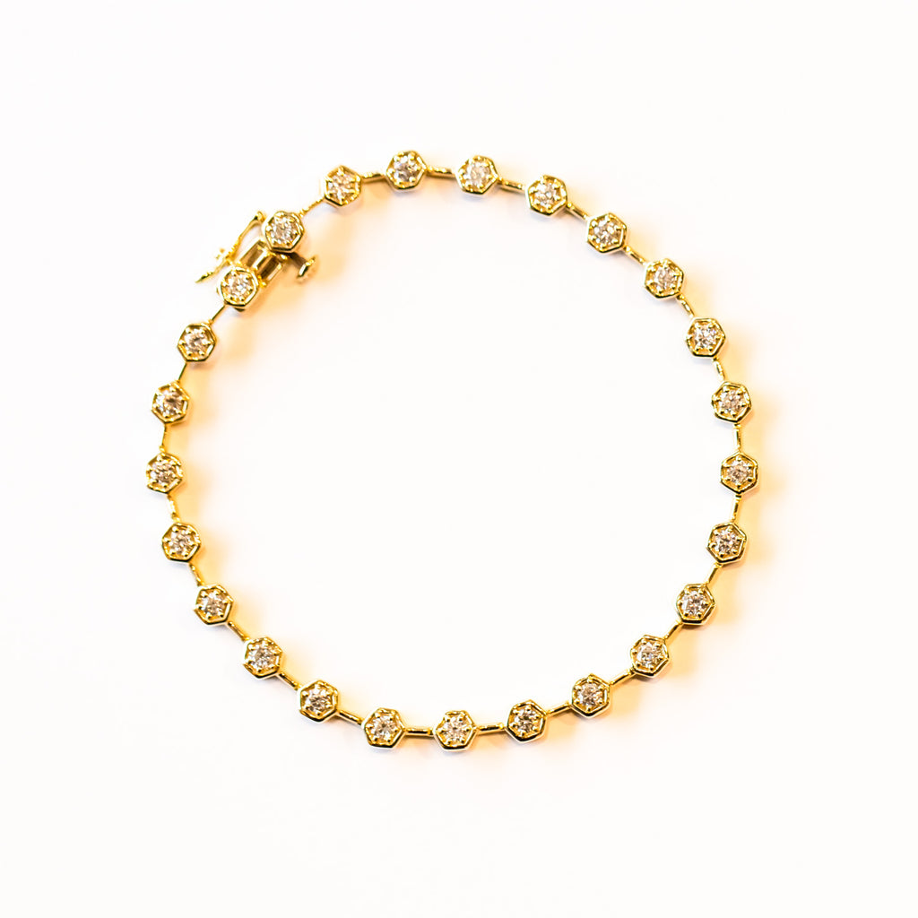 A yellow gold diamond tennis bracelet made up of hexagon-shaped links set with brilliant round diamonds.