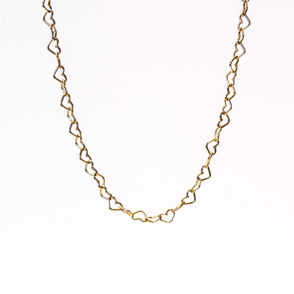 A gold chain necklace made up of heart-shaped links.