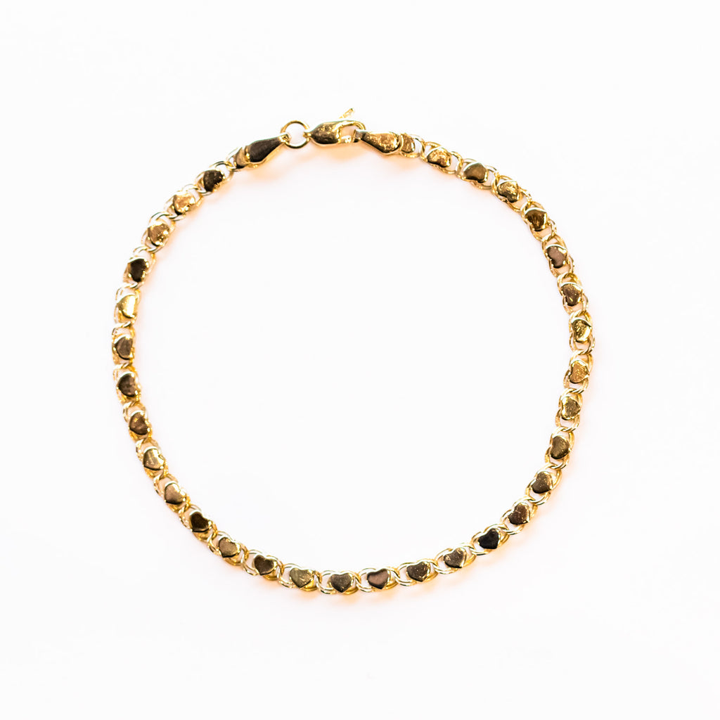 A gold chain bracelet made up of polished gold heart links.