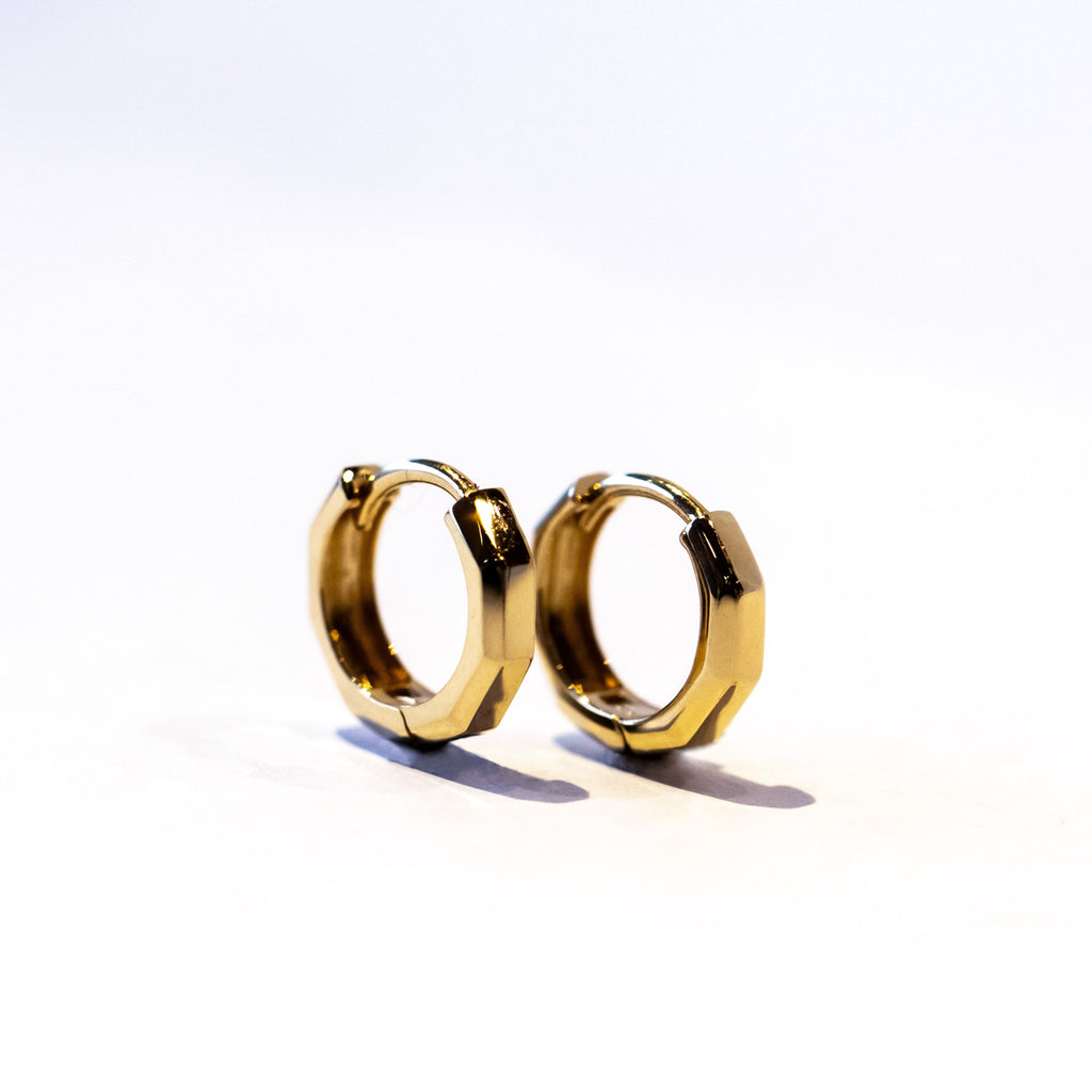 Petite gold hoop earrings with a faceted design.