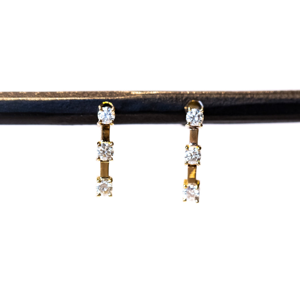 Earrings made of three prong set round diamonds spaced out by flexible gold bars in between.