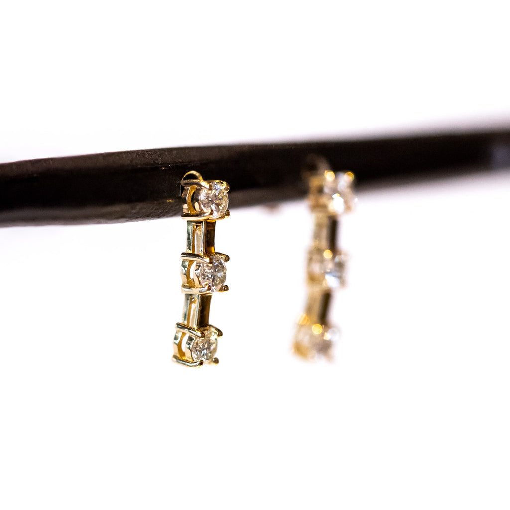 Earrings made of three prong set round diamonds spaced out by flexible gold bars in between.