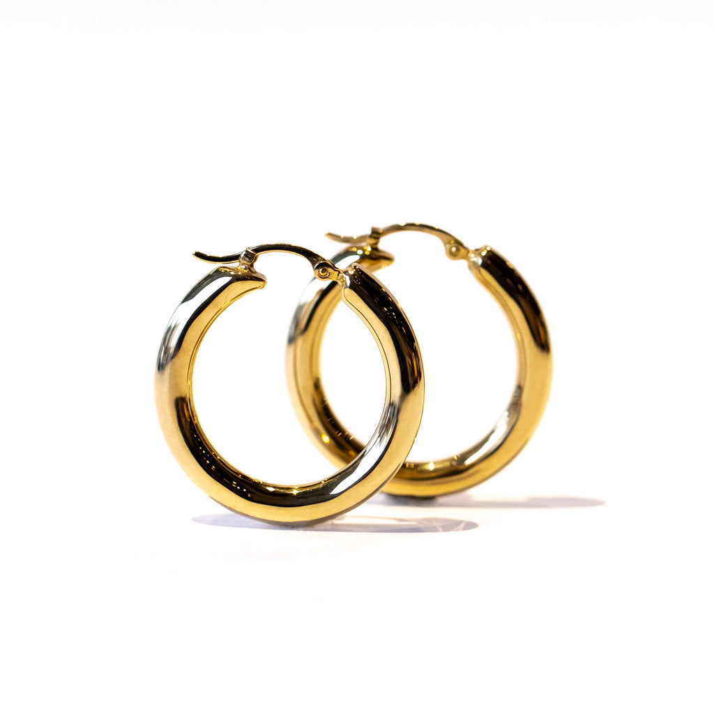 A gold hoop earring with a wide round profile.