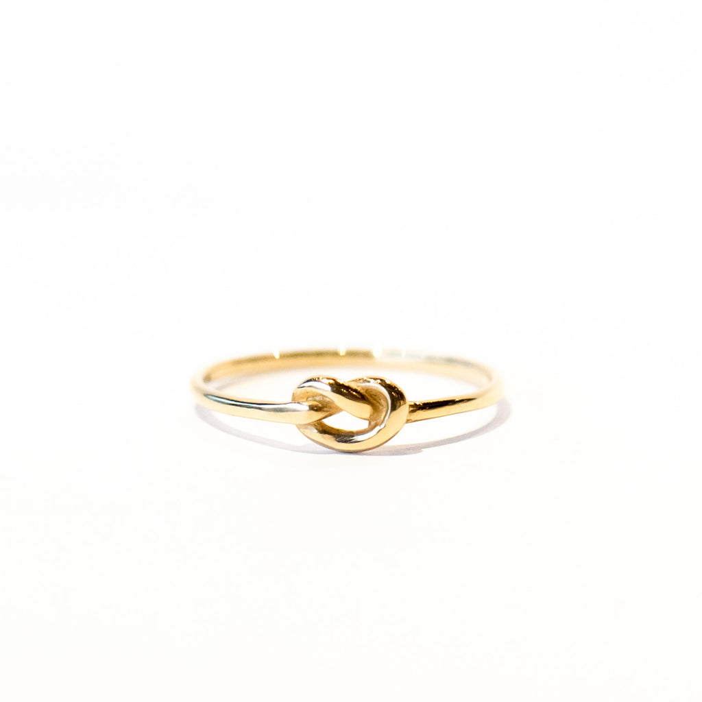 A dainty gold wire band with a knot tied at the top.