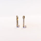 A petite gold hoop earring with a row of round pave set diamonds down the front.