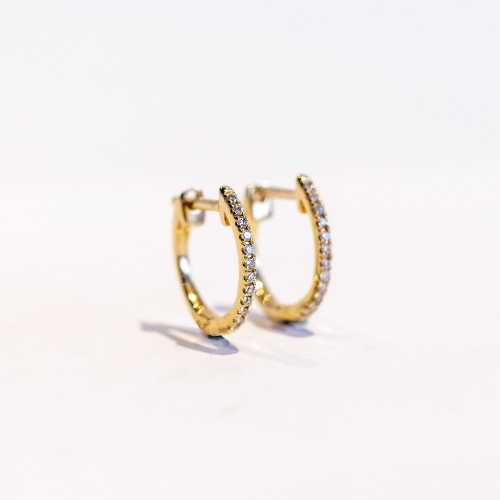 A petite gold hoop earring with a row of round pave set diamonds down the front.