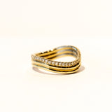 A three-banded wavy gold ring with one of the bands covered in a row of diamonds.