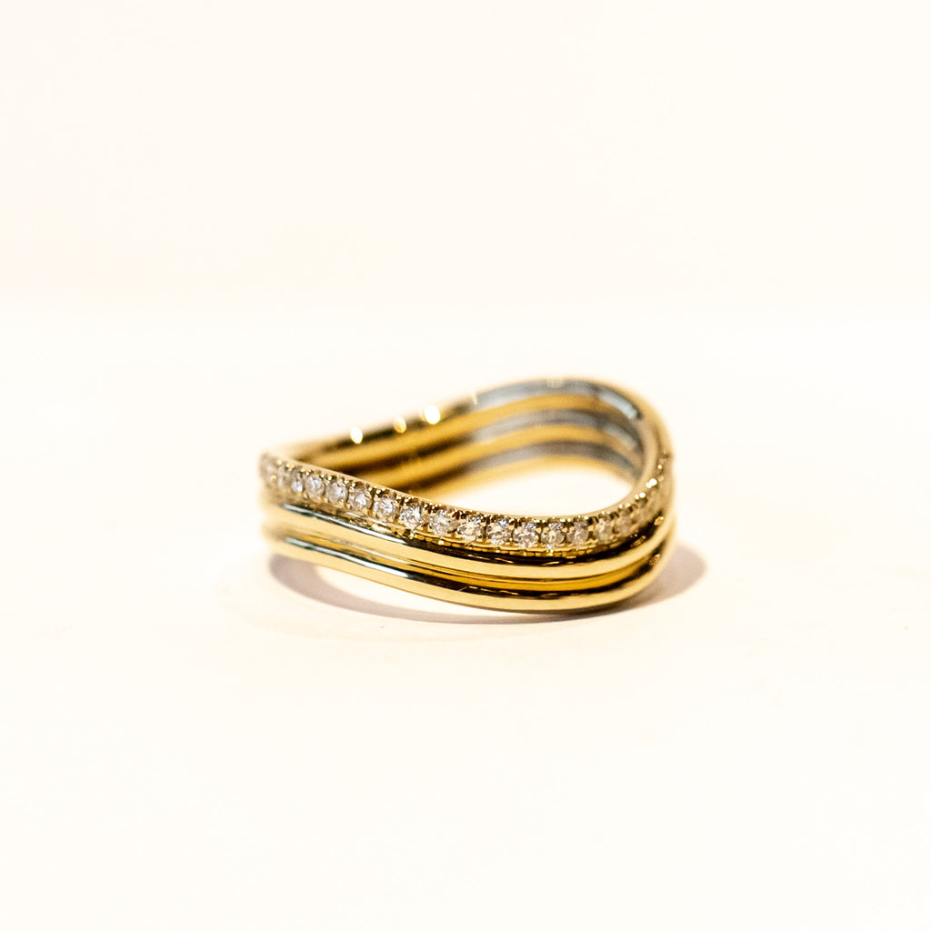 A three-banded wavy gold ring with one of the bands covered in a row of diamonds.