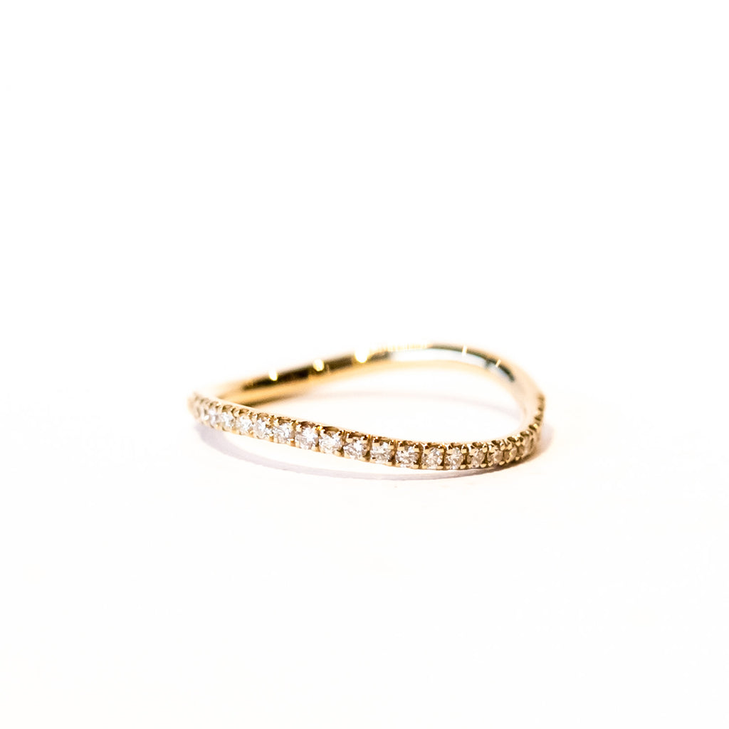 A thin gold wavy band with a row of diamonds along the top.