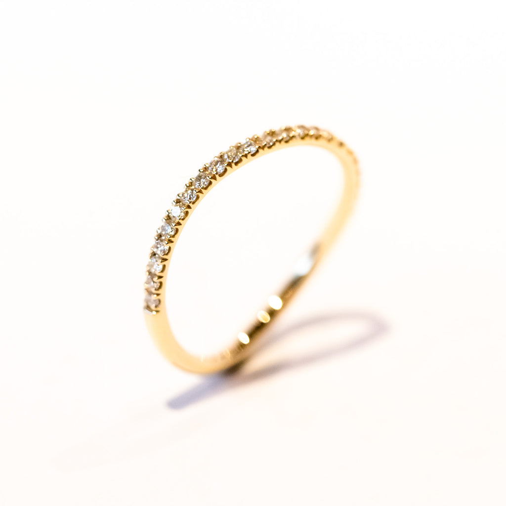 A thin gold wavy band with a row of diamonds along the top.