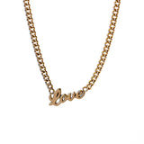A classic gold curb chain necklace with the word "love" in script at the center.