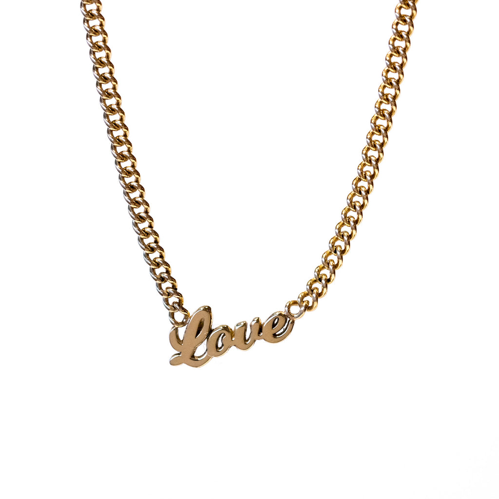 A classic gold curb chain necklace with the word "love" in script at the center.