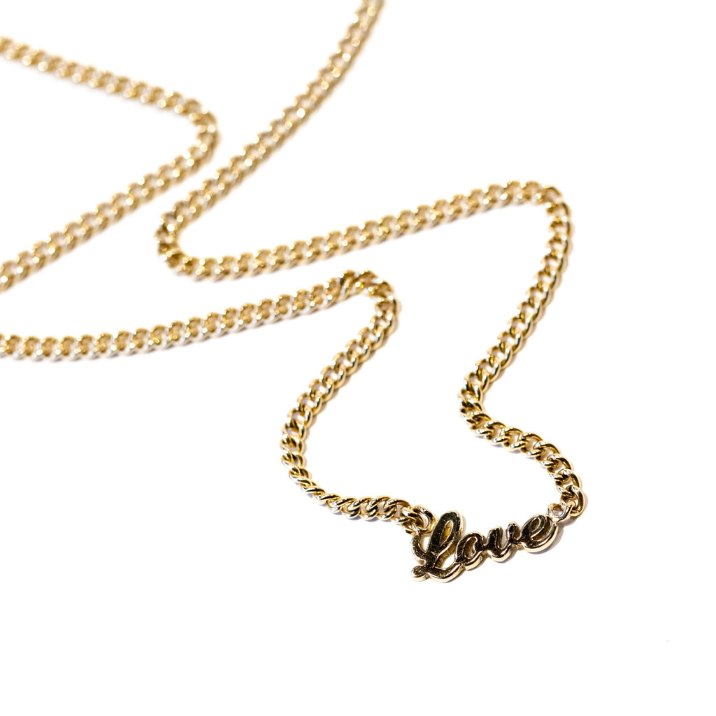 A classic gold curb chain necklace with the word "love" in script at the center.