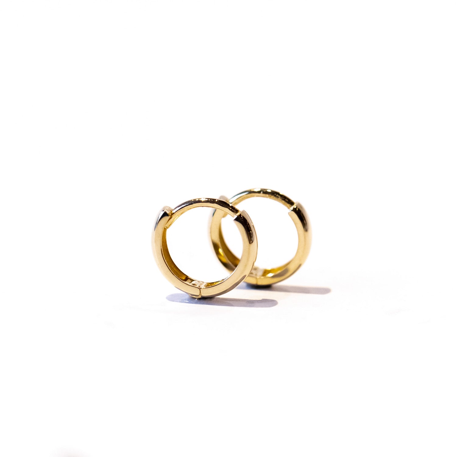 A petite gold hoop earring with a wide profile.