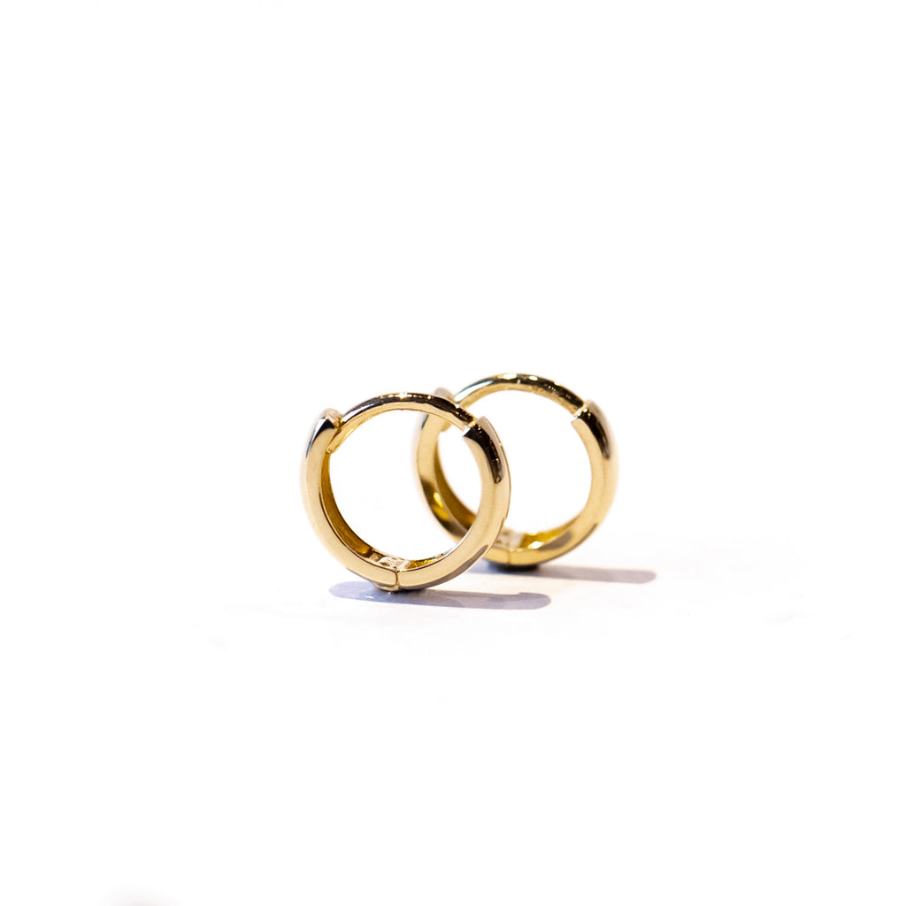 A petite gold hoop earring with a wide profile.