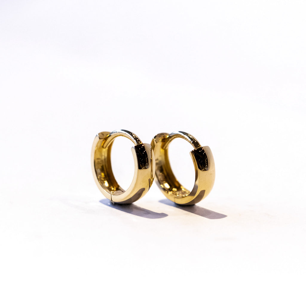 A petite gold hoop earring with a wide profile.