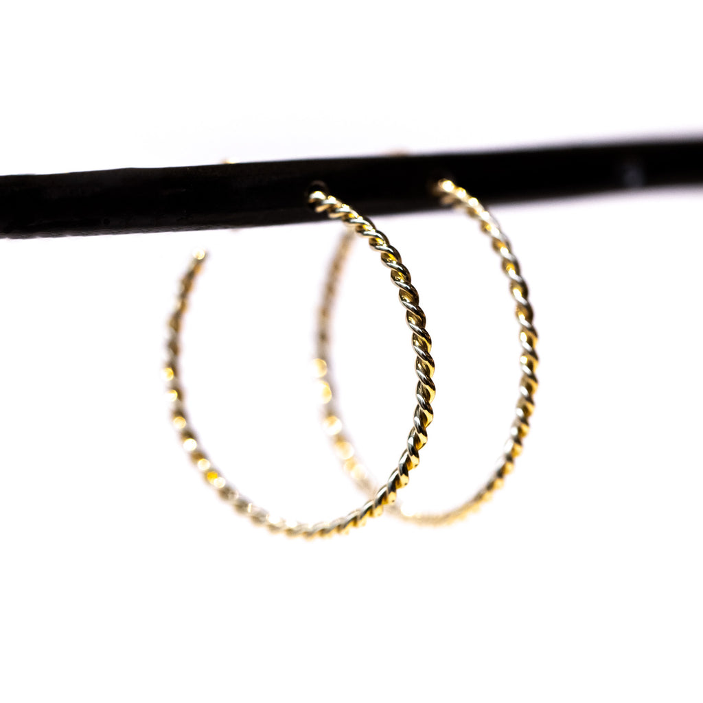 A pair of skinny gold twisted wire hoop earrings.