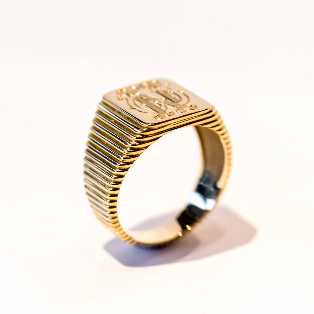 A ribbed-texture signet ring with a rectangular top and fancy engraving "NW"