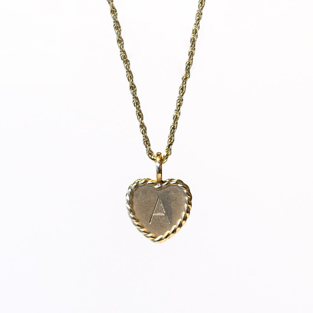 A twisted gold cable necklace with a dainty engraved heart charm with the letter "A"