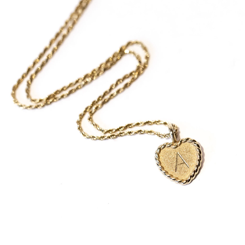 A twisted gold cable necklace with a dainty engraved heart charm with the letter "A"