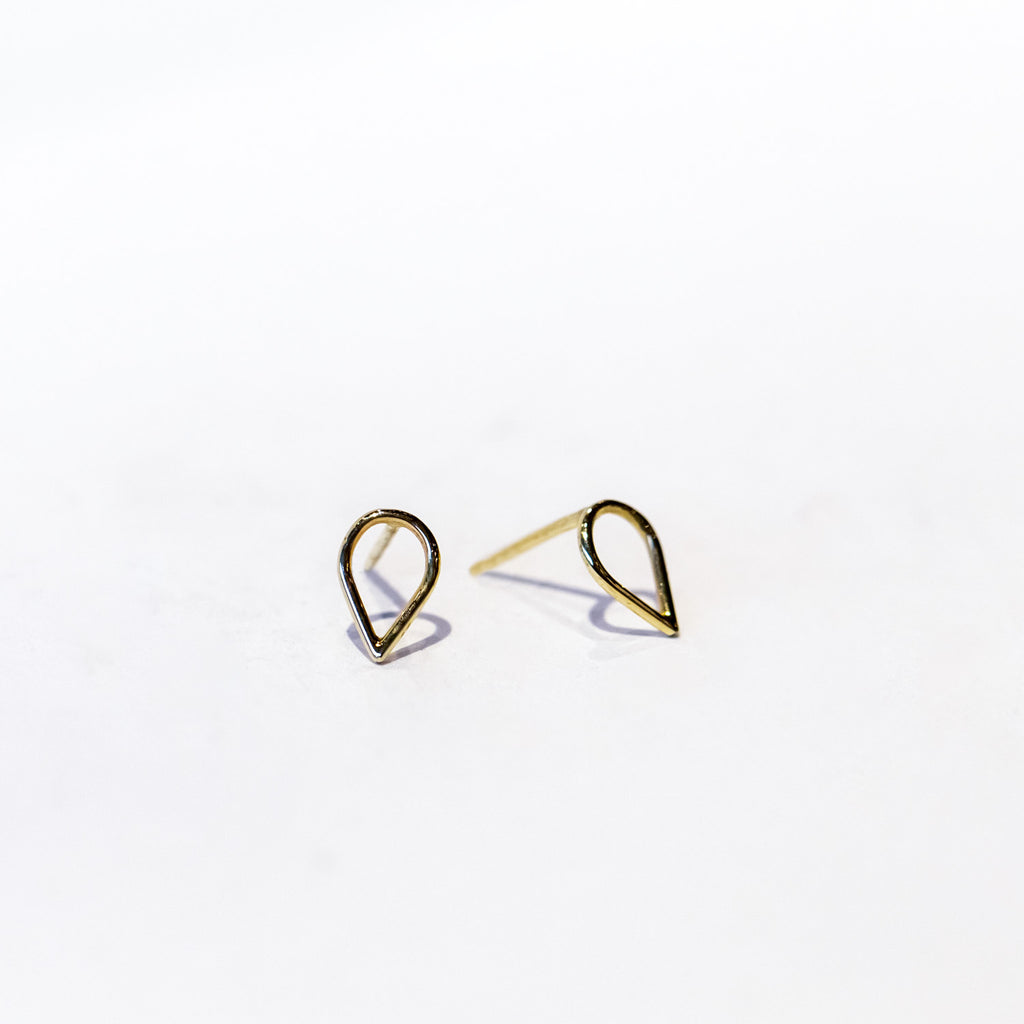 A pair of small gold stud earrings in an open teardrop outline.