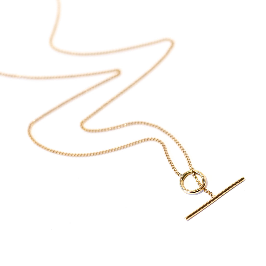 A thin gold chain necklace with a toggle closure.