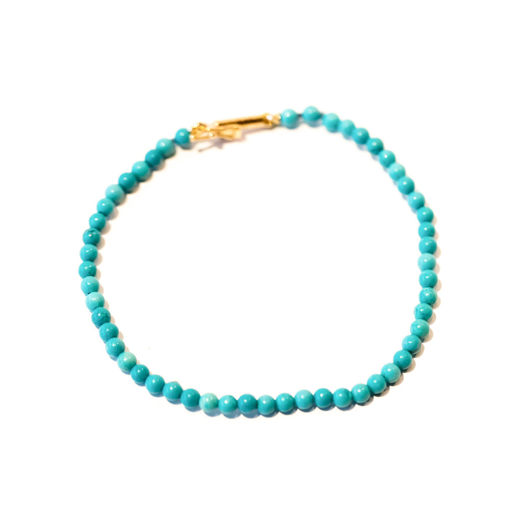 A dainty turquoise bead bracelet with gold clasp.