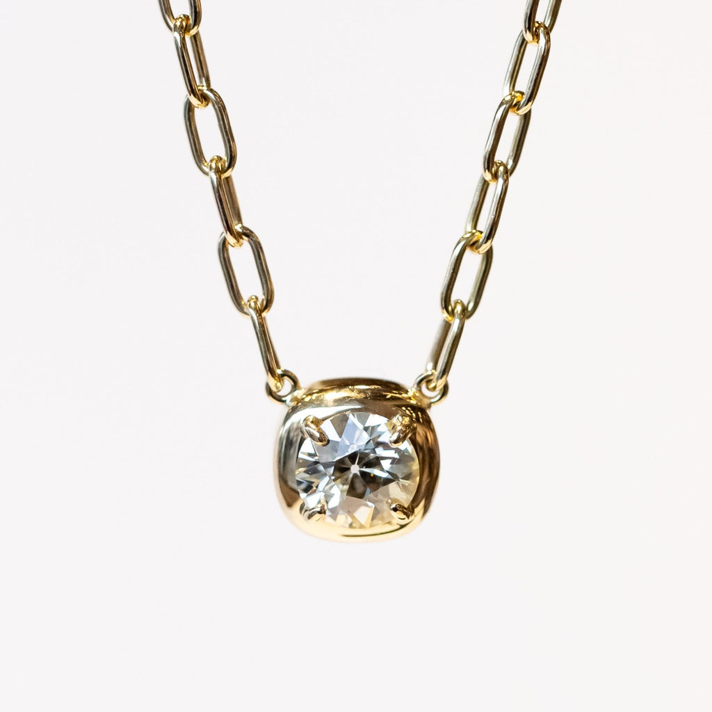 A yellow gold chain necklace of oval links with a prong set diamond on a gold cushion mounting stationed at the center.