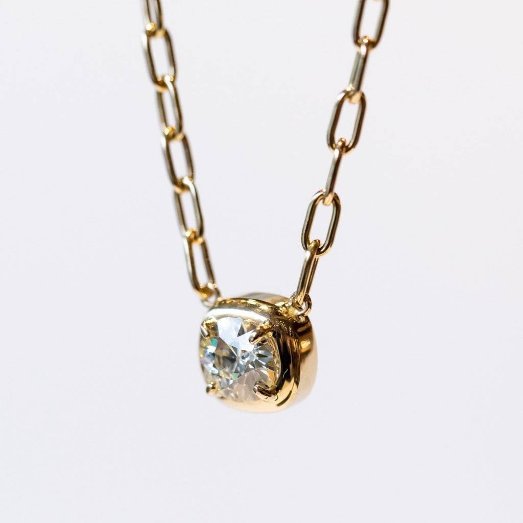 A yellow gold chain necklace of oval links with a prong set diamond on a gold cushion mounting stationed at the center.