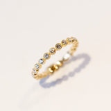 A yellow gold diamond eternity band with round white diamonds set in bezels with milgrain edges.