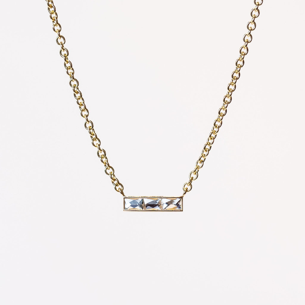 A bar-style diamond station necklace set with three rectangular French cut diamonds in a horizontal bar with a classic yellow gold cable chain.
