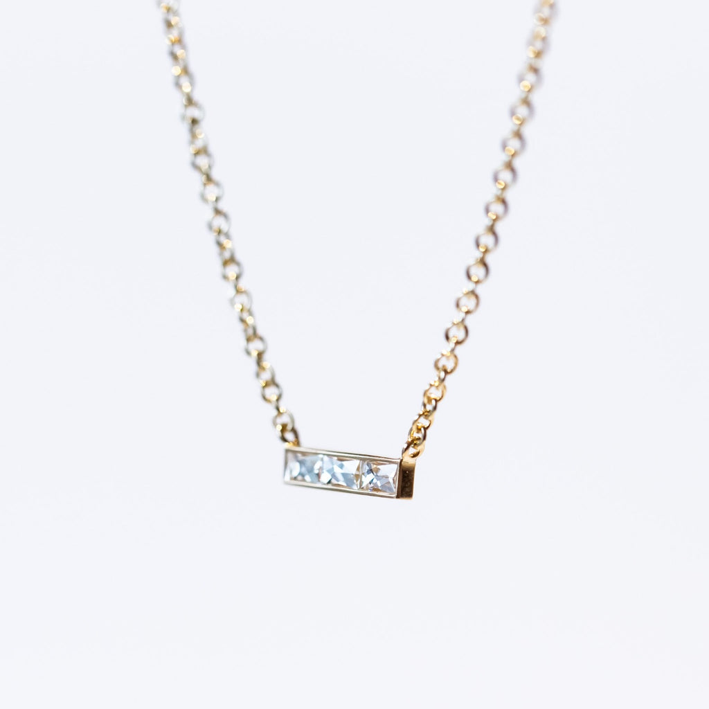 A bar-style diamond station necklace set with three rectangular French cut diamonds in a horizontal bar with a classic yellow gold cable chain.