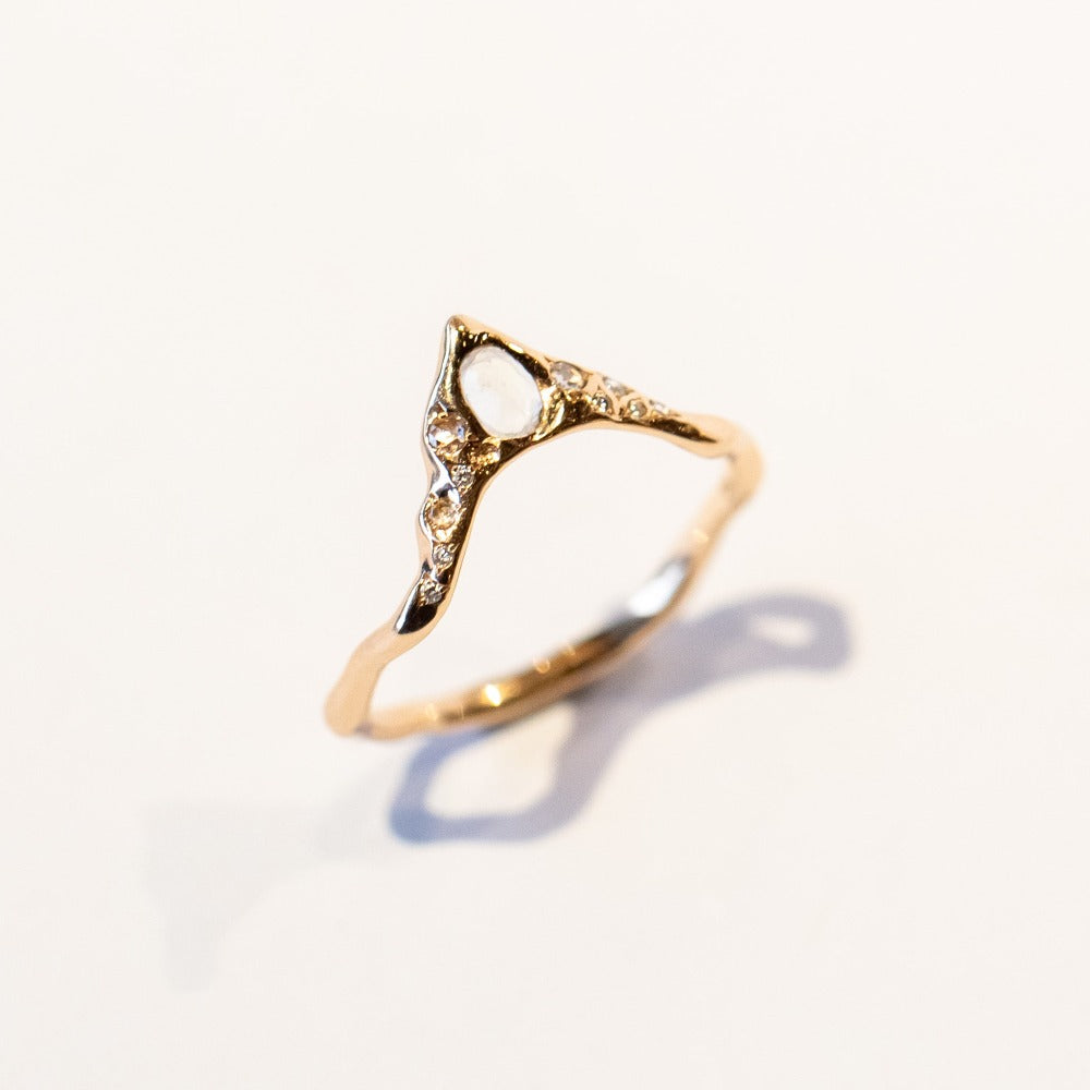 A rose gold, peaked contour band with a white moonstone and sparkling diamond accents.