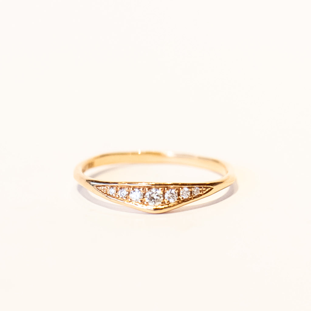 A dainty rose gold band featuring an asymmetrically peaked top set with pave diamonds.