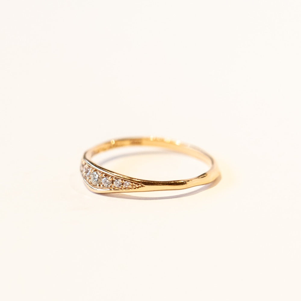 A dainty rose gold band featuring an asymmetrically peaked top set with pave diamonds.
