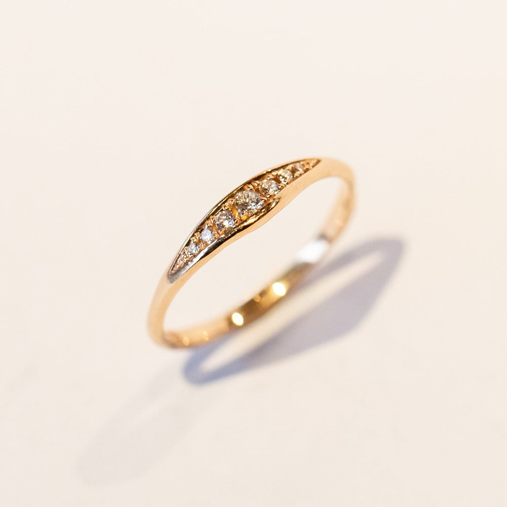 A dainty rose gold band featuring an asymmetrically peaked top set with pave diamonds.