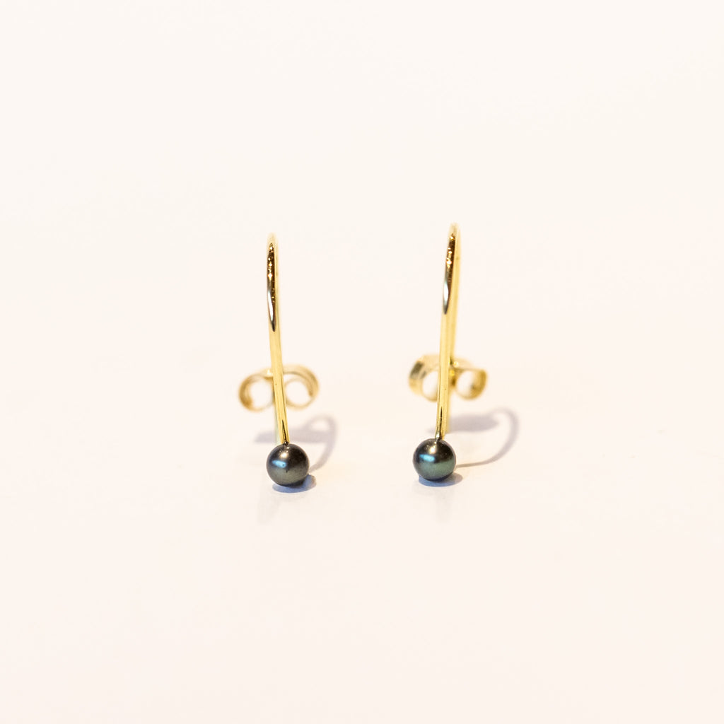 Dainty gold wire hook earrings with tiny black pearls at the end.