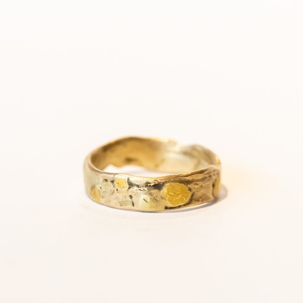 An organic textured yellow gold wide wedding band.