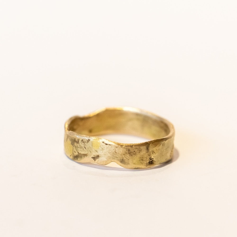 An organic textured yellow gold wide wedding band.